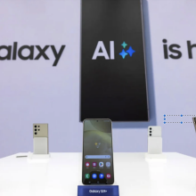 Samsung phones in front of a display that says "Galaxy AI is here"