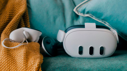 a meta quest 3 headset and its controllers on a teal couch and a yellow blanket