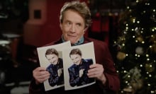 A man holds up two photos of himself.