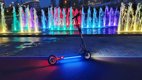 A scooter in front of a colorful fountain