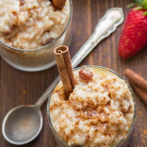 Two Glasses of Vegan Rice Pudding with Cinnamon Sticks and Strawberries