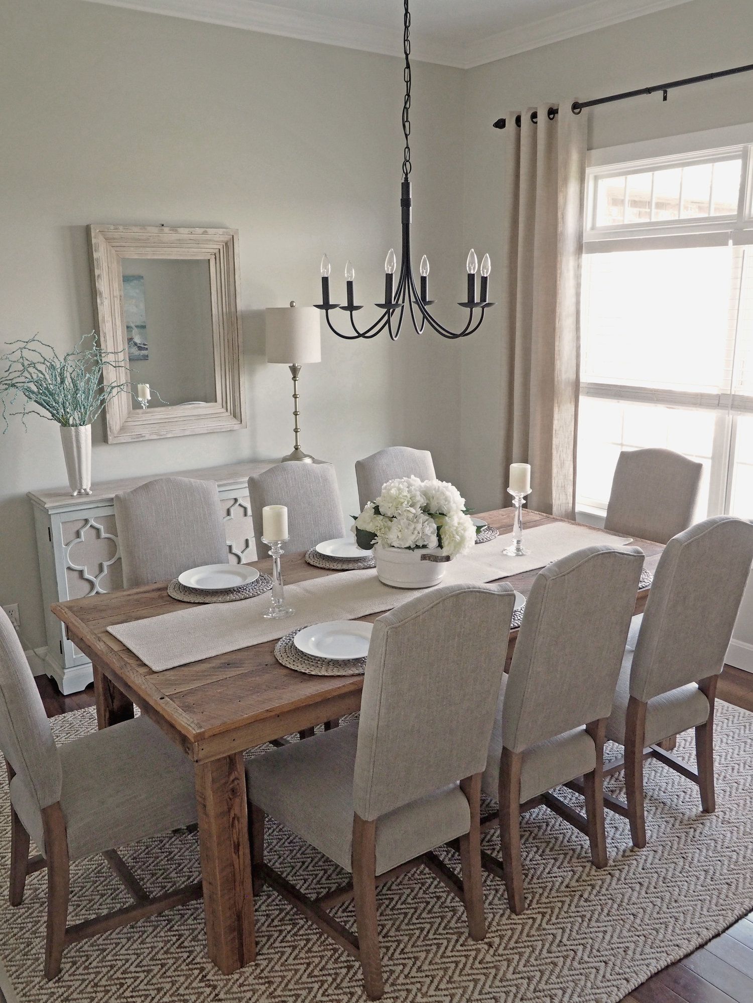 the dining room table is set with white flowers and place settings for ...