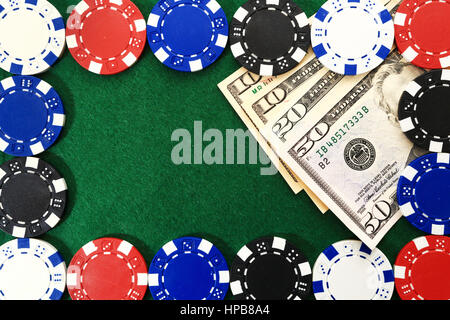 Money under gaming chips on green table. Games of chance background. Free space for text on green textured background between casino chips. Games chip Stock Photo