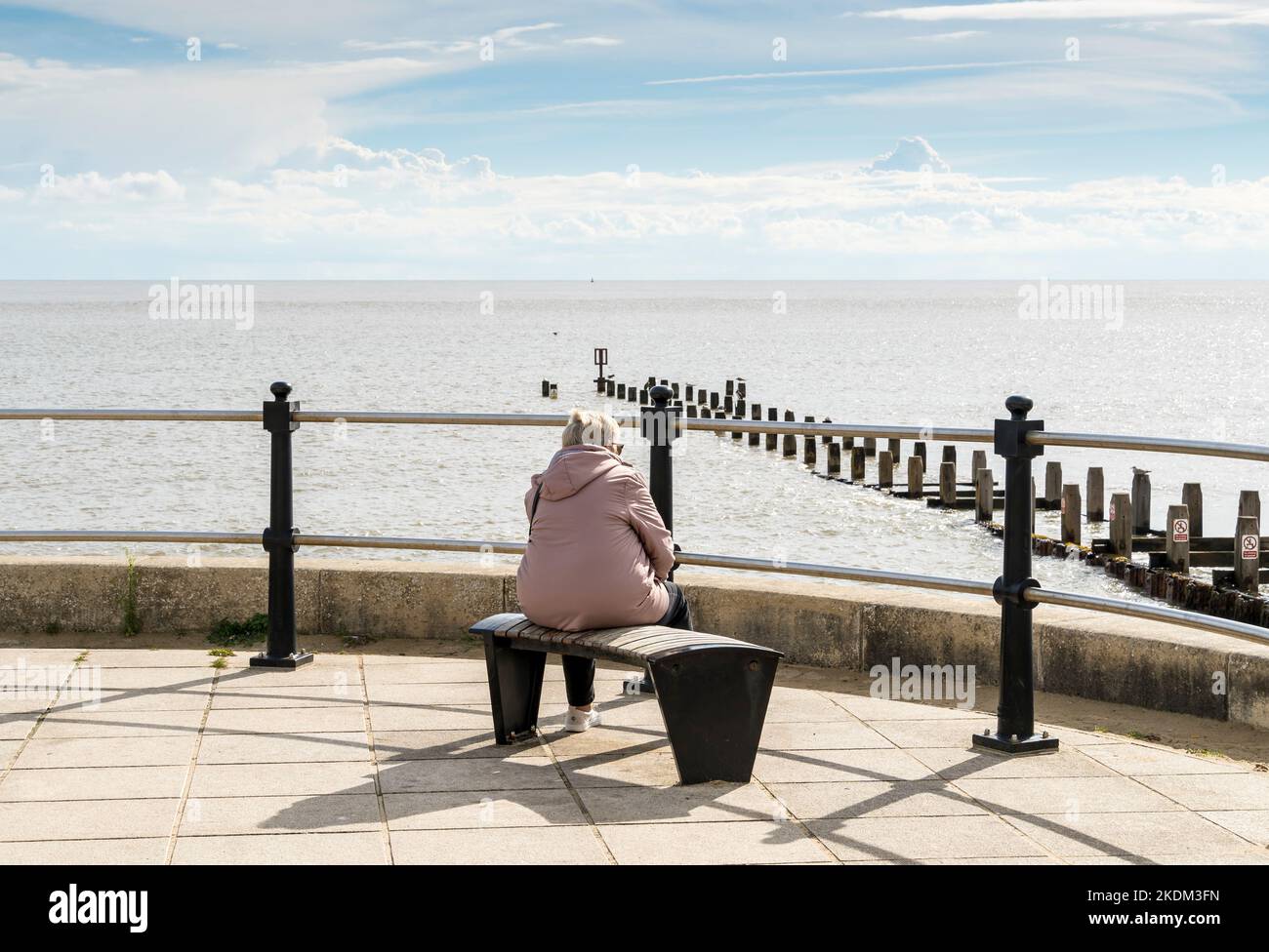 Lone lady sat on bench looking out to sea Lowestoft seafront parade suffolk 2022 Stock Photo