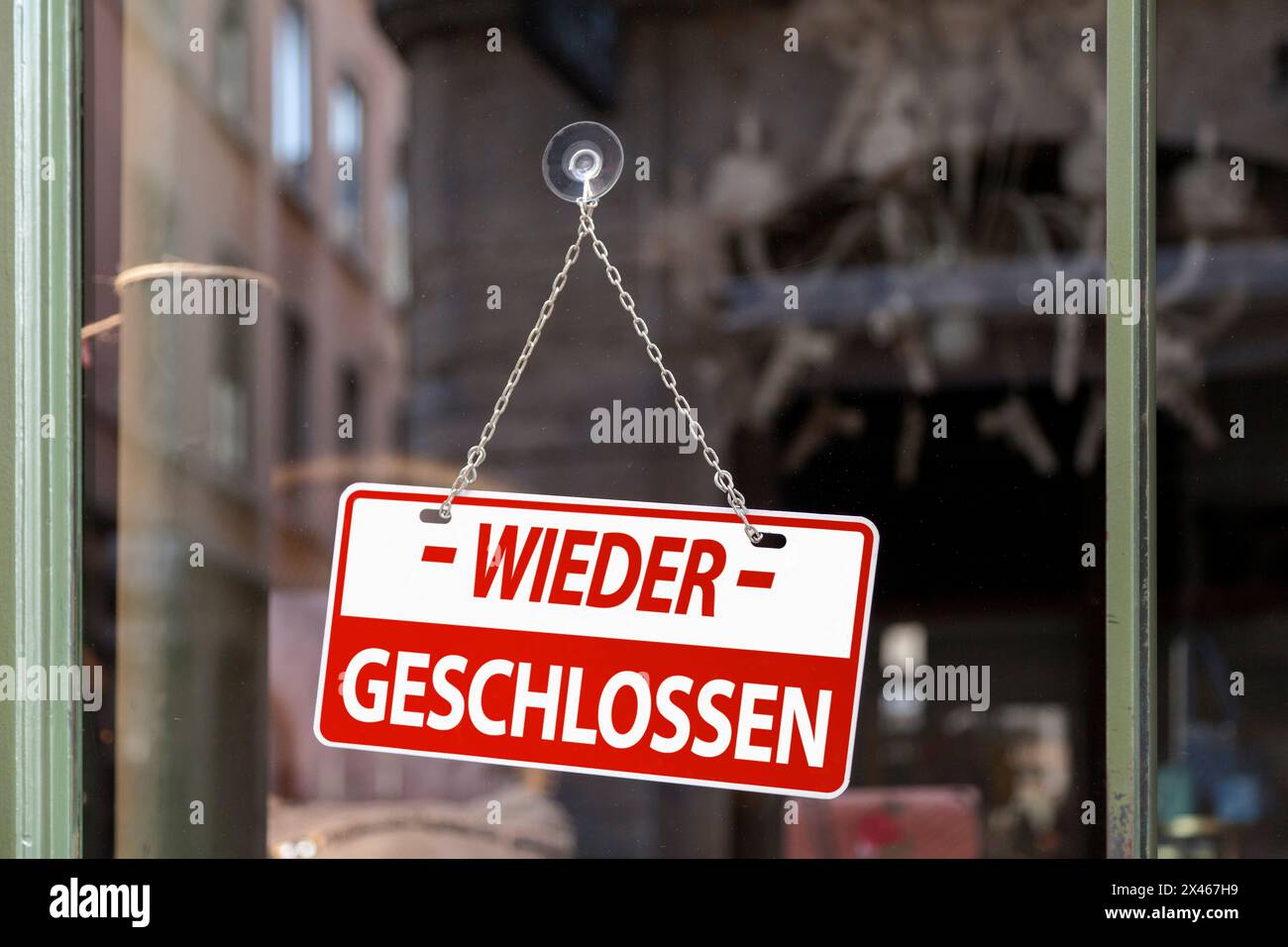 Close-up on a red sign in a window written inside in German 'Wieder geschlossen' meaning in English 'Closed again'. Stock Photo