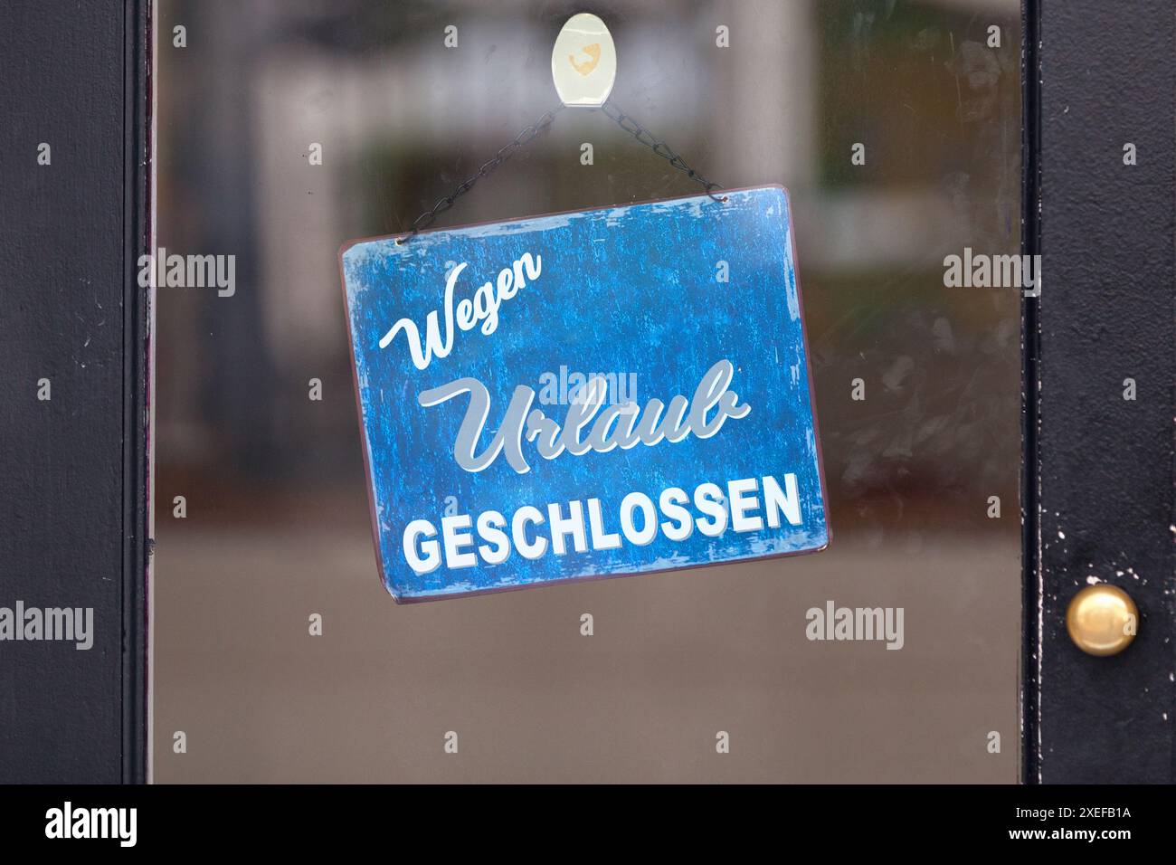 Red open sign with written in German 'Wegen Urlaub geschlossen' meaning in English 'Closure for holidays'. Stock Photo