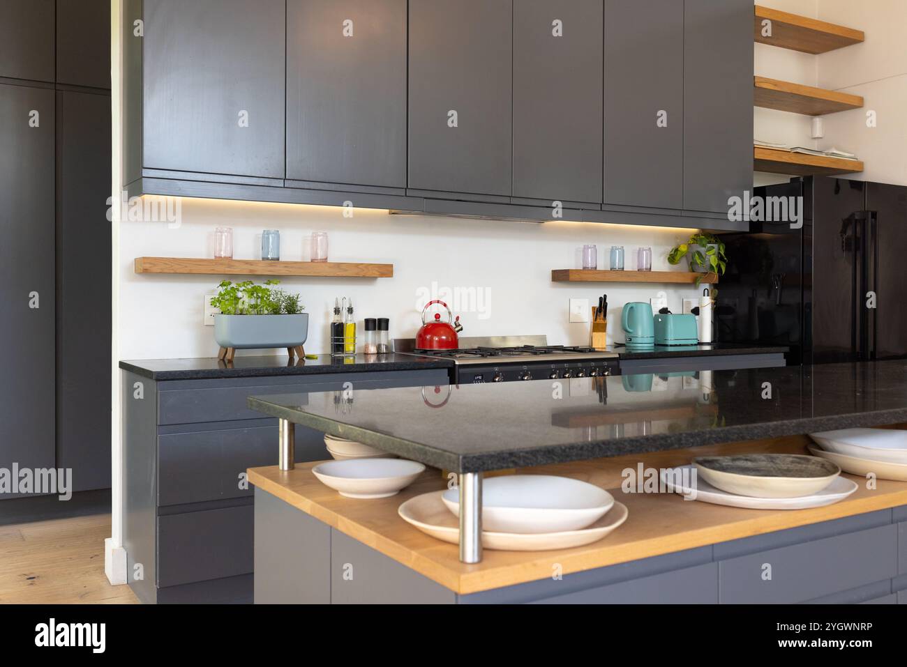 Modern kitchen with sleek cabinets and red kettle on countertop, at home Stock Photo