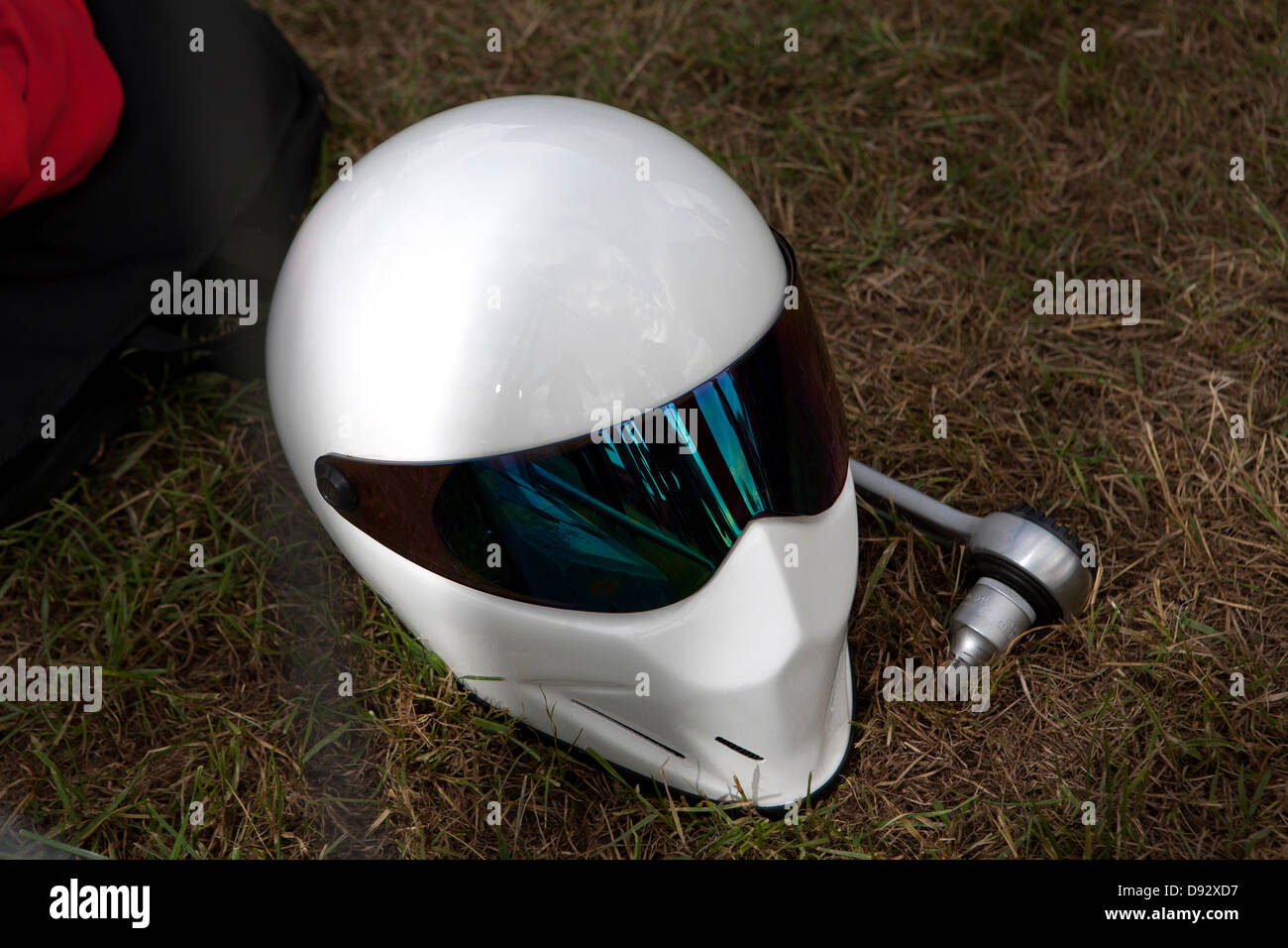 A sleek modern crash helmet lying on grass next to socket wrench Stock Photo