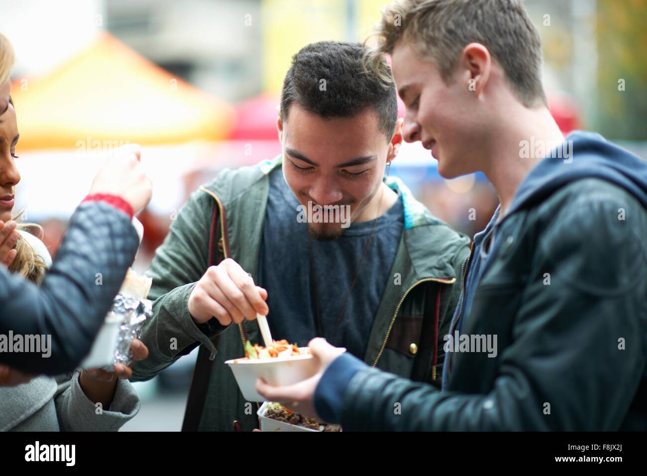 Group of young adults eating takeaway food, outdoors Stock Photo