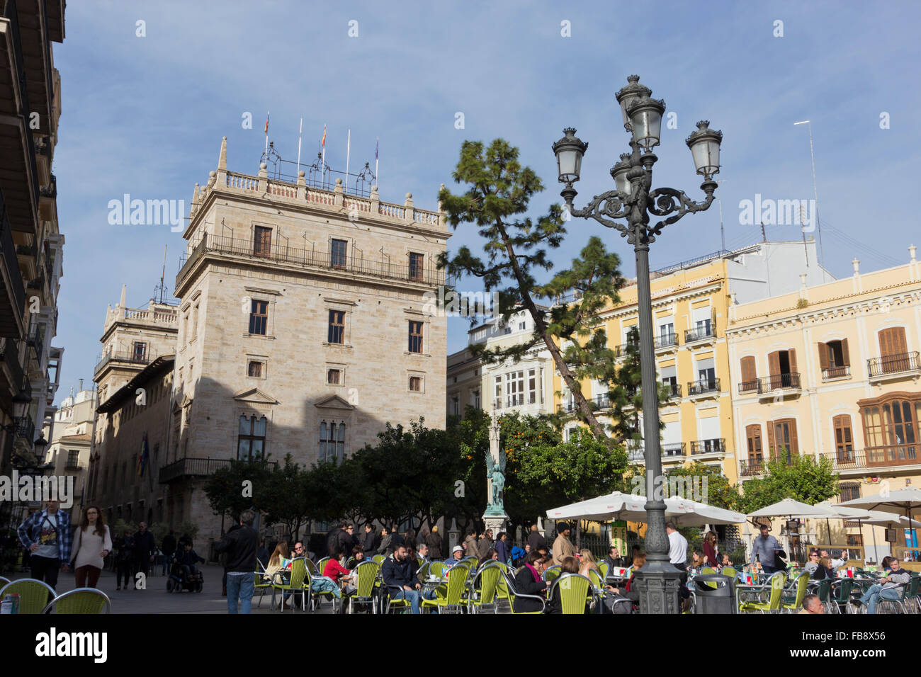 Tourists sat in La Plaza de la Virgen, in the background El palacio de la Generalidad, Valencia, Spain. Stock Photo