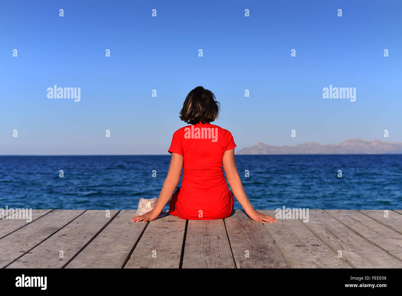 Beautiful single mature woman sat on edge of jetty at the Balearic Island of Majorca, Spain. Stock Photo