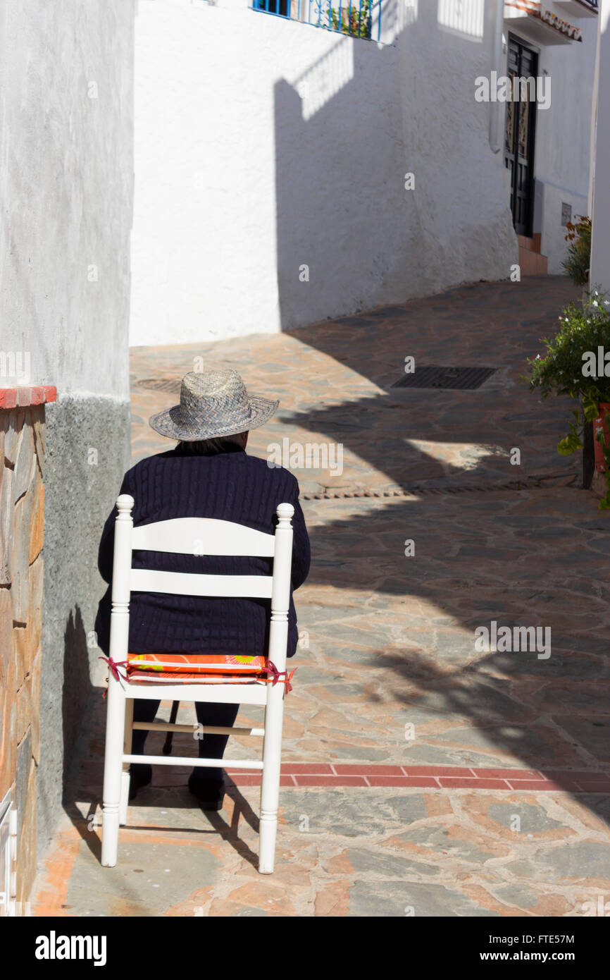 Back view of Spanish lady sat in a chair outside her house in the village of Totalan, Malaga, southern Spain. Stock Photo