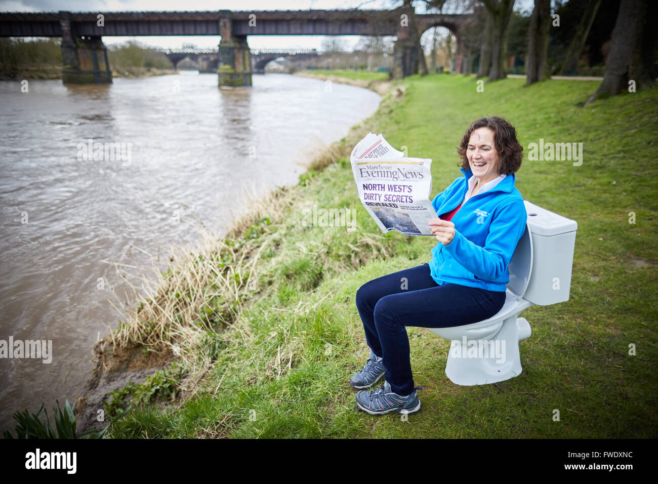 Sat on a toilet reading newspaper loo potty urinal sitting using sewage Stock Photo