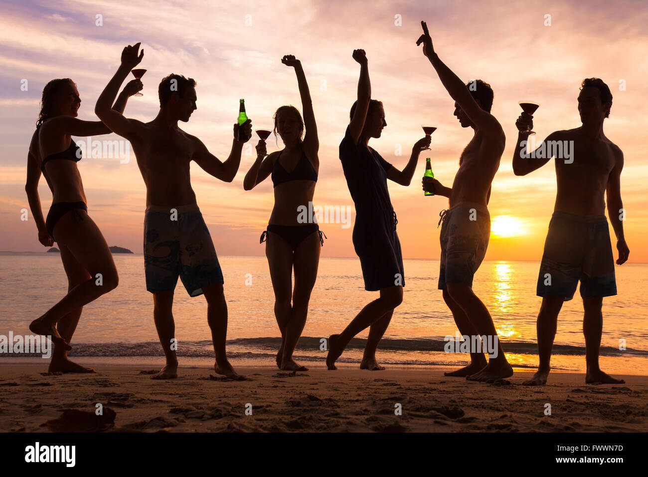 beach party, group of young people dancing, friends drinking beer and cocktails at sunset Stock Photo