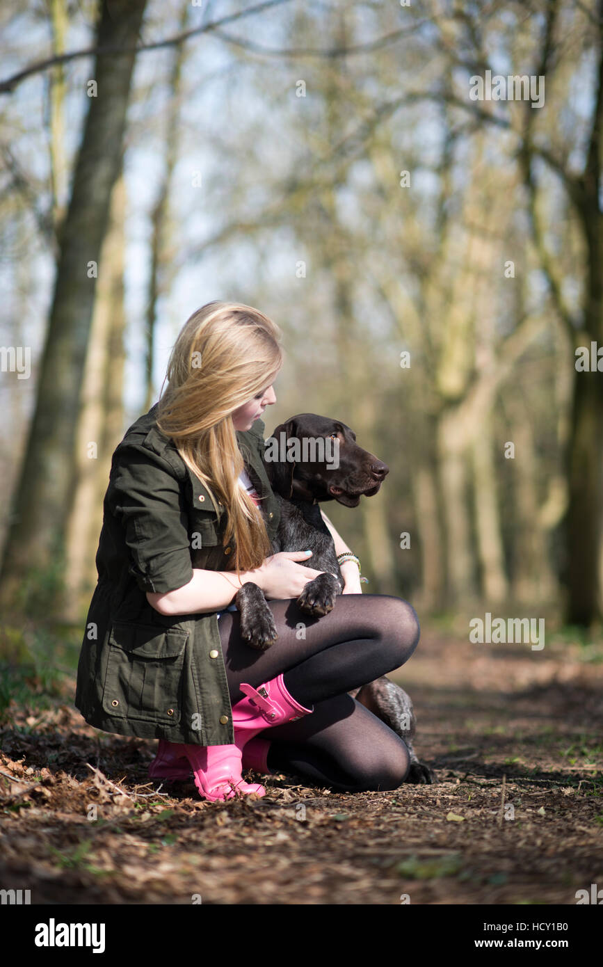 A girl takes her German short-haired pointer for a walk in woods near Ashmore in Dorset, UK Stock Photo