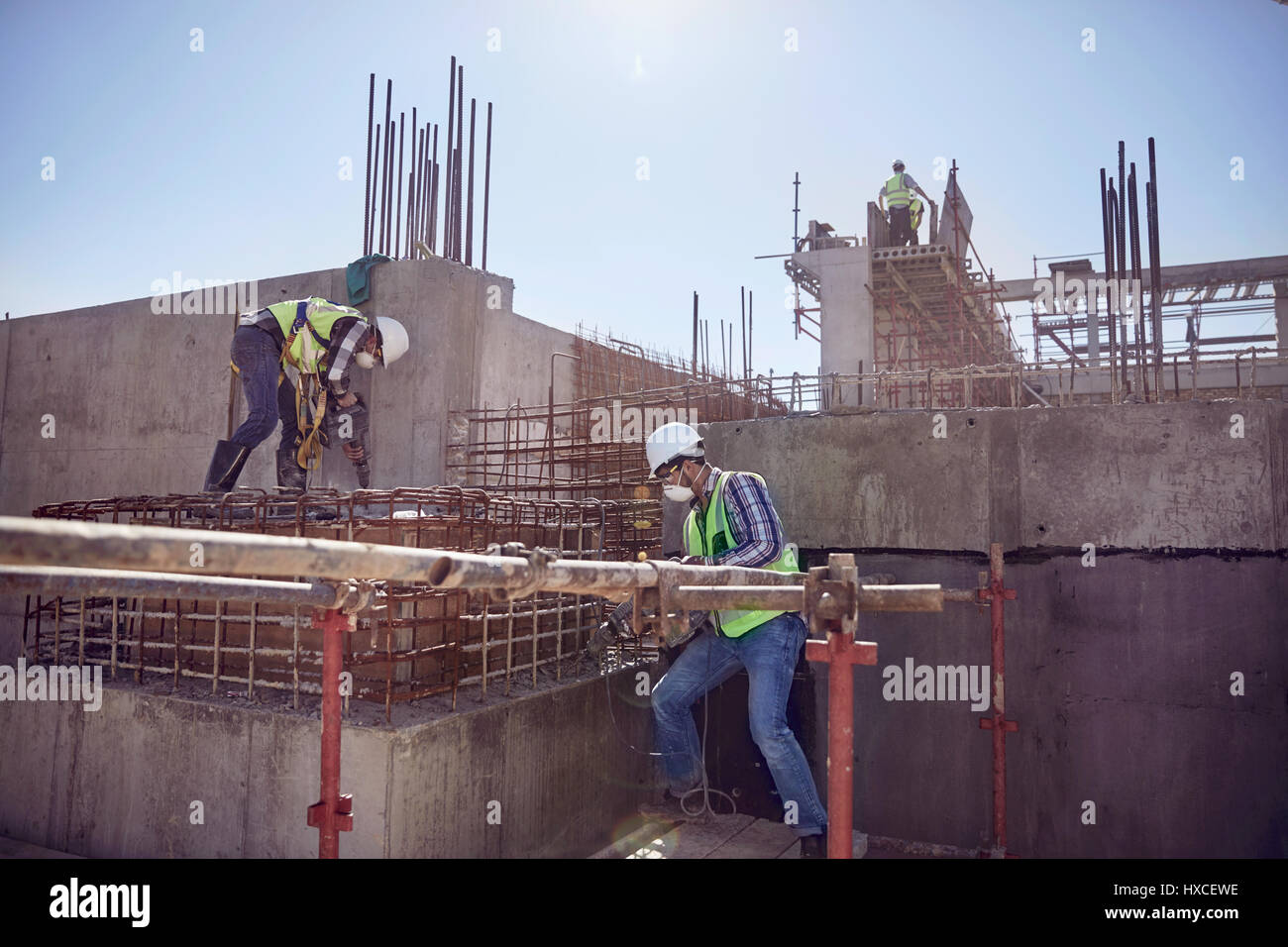 Construction workers working at sunny construction site Stock Photo