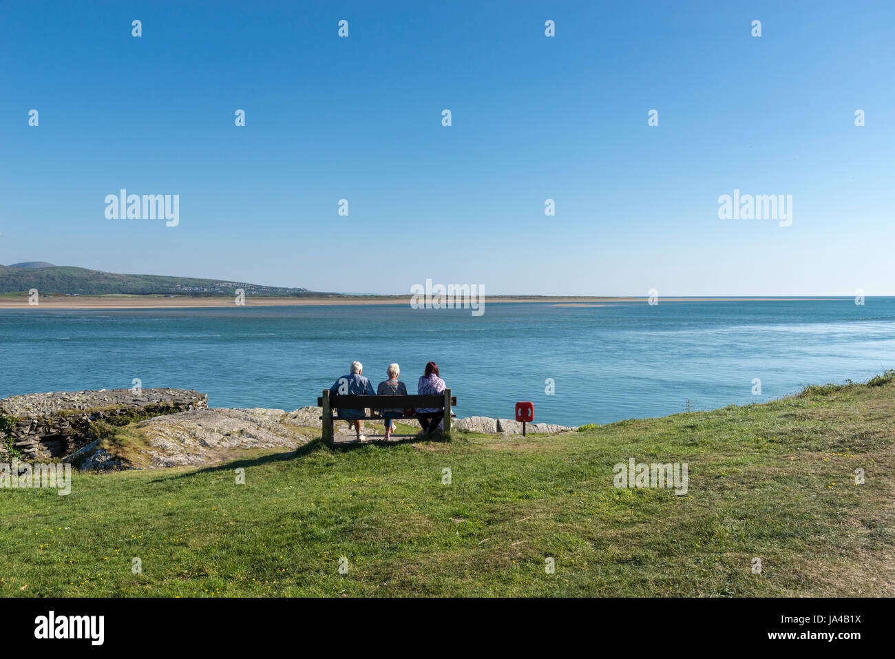 Family sat overlooking the estuary at Borth-y-Gest near Porthmaodg in North Wales. Stock Photo