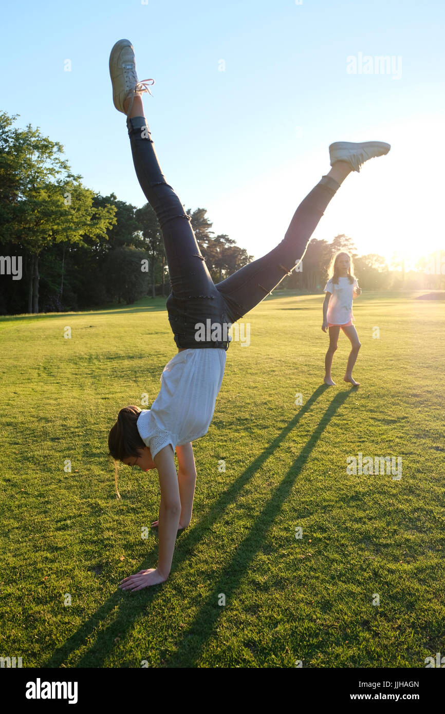 A teenage girl doing a handstand watched by her sister. Stock Photo