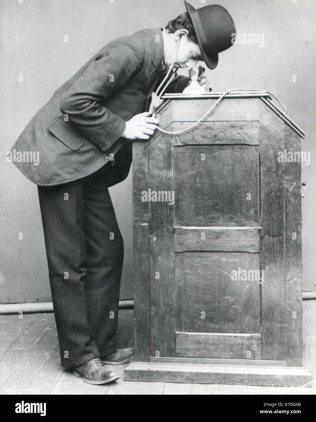 New York - A man looking into the Edison 'peep-hole' Kinetoscope. It is equipped with hearing tubes for synchronized sound. This was the first important motion-picture exhibiting machine. Stock Photo