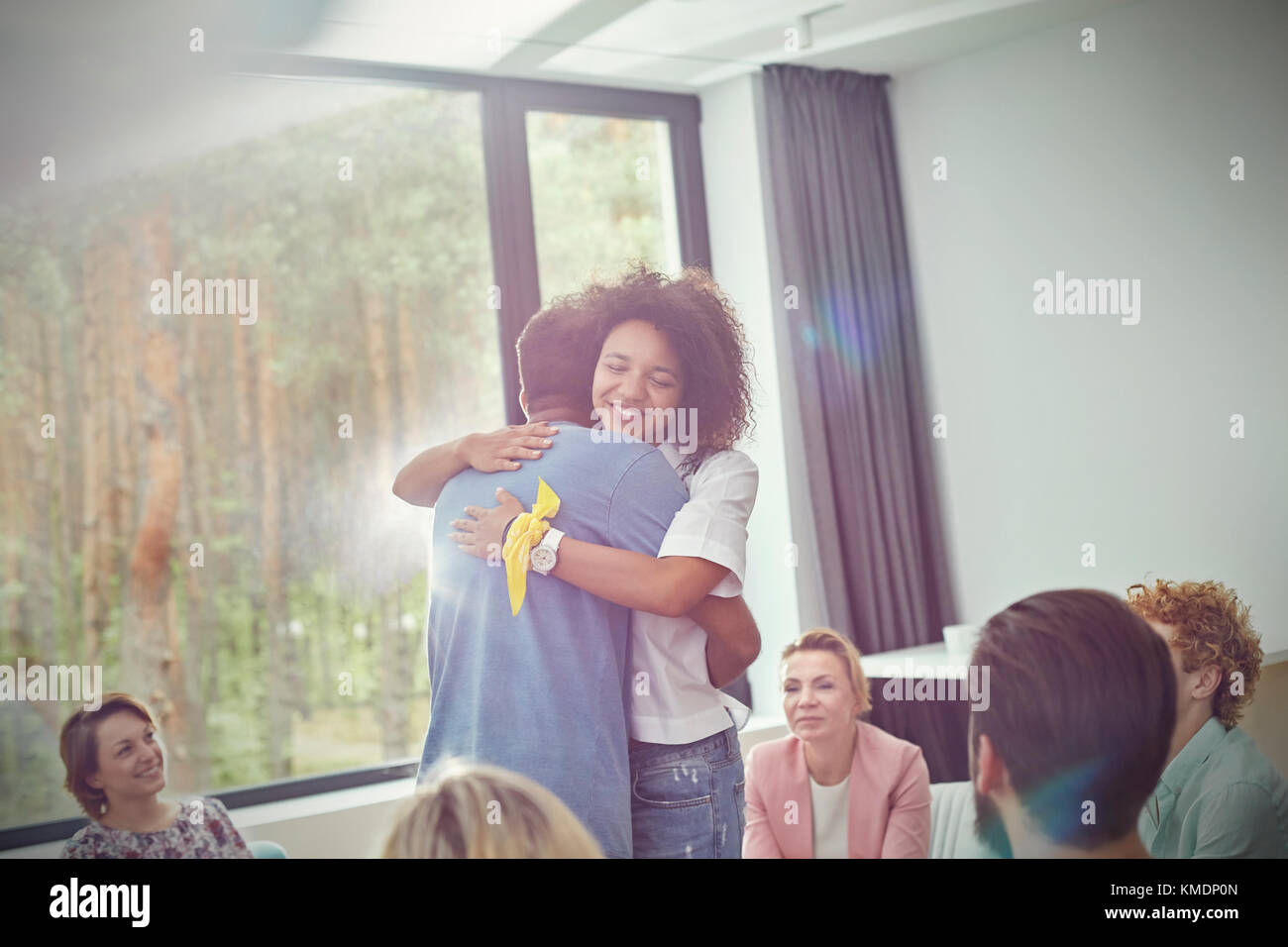 Man and woman hugging in group therapy session Stock Photo