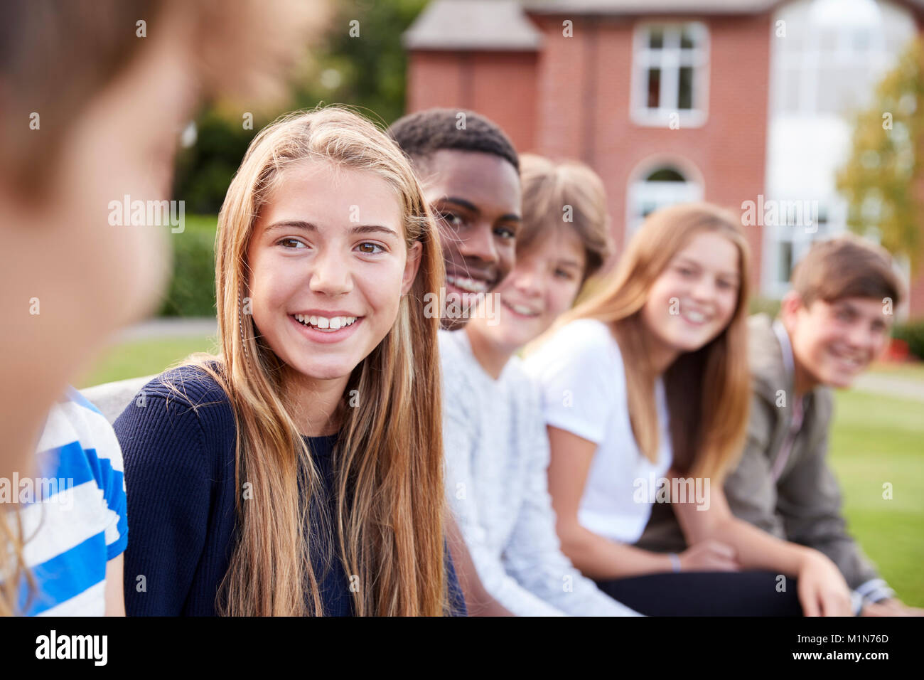 Group Of Teenage Students Sitting Outside School Buildings Stock Photo