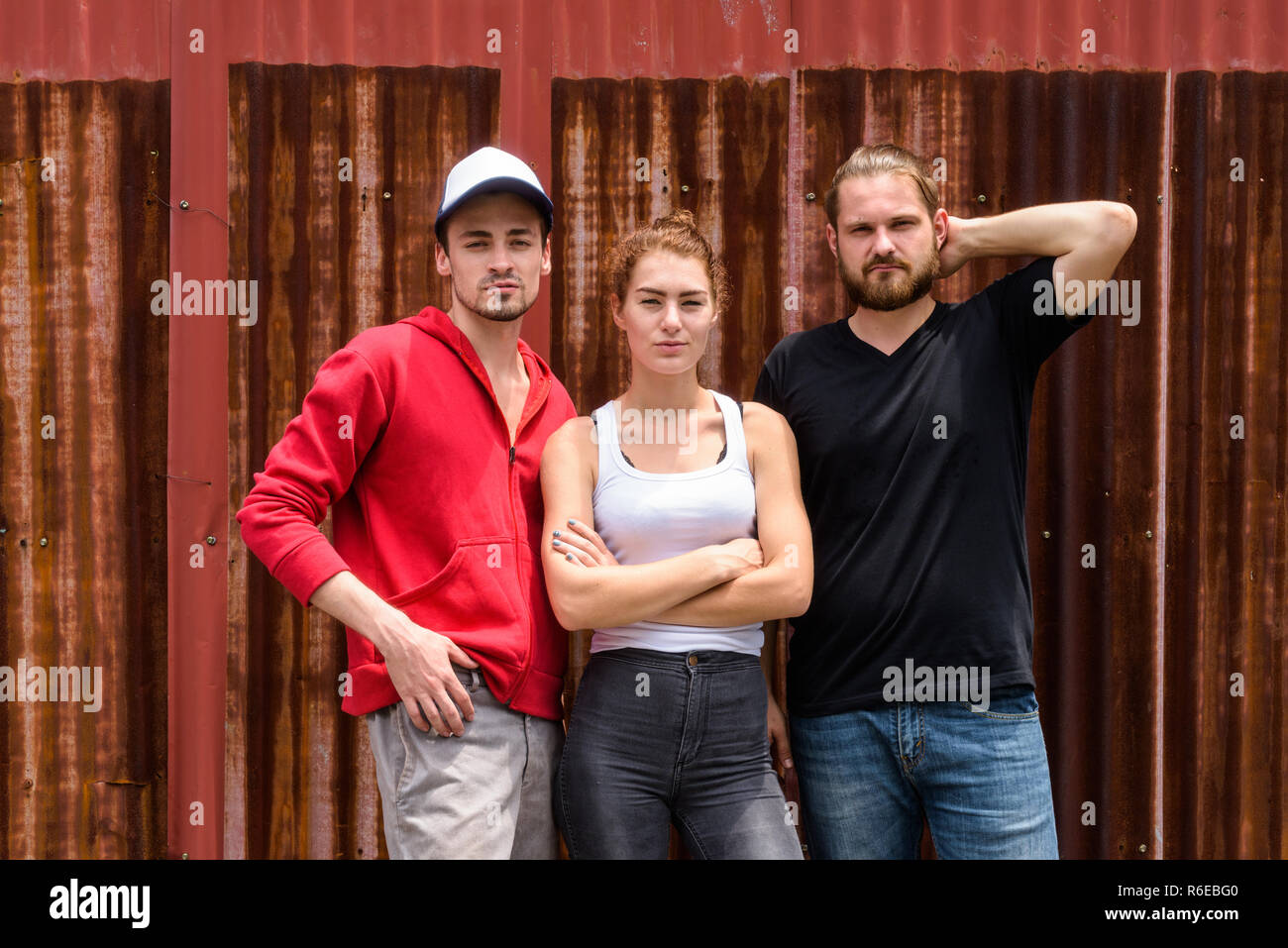 Group of friends posing together against old rusty sheet wall Stock Photo