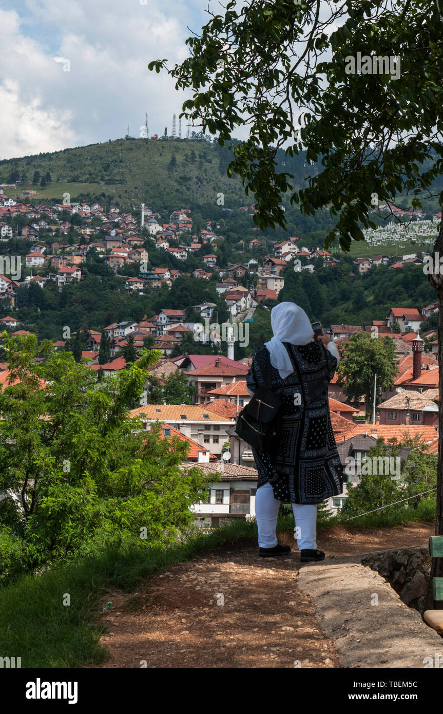 Sarajevo, Bosnia: veiled woman looking at the skyline of the city with Dinaric Alps and Miljacka River from the top of Zuta Tabija (Yellow Fortress) Stock Photo