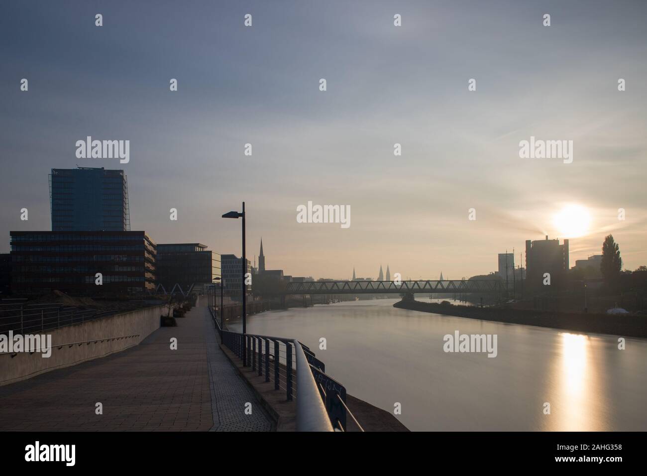 Lange Exposition der Überseestadt in Bremen, Deutschland mit Bürogebäude und bewölkter Himmel bei Sonnenaufgang Stockfoto