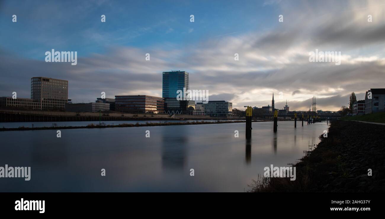 Lange Exposition der Überseestadt in Bremen, Deutschland mit Bürogebäude und bewölkter Himmel bei Sonnenaufgang Stockfoto