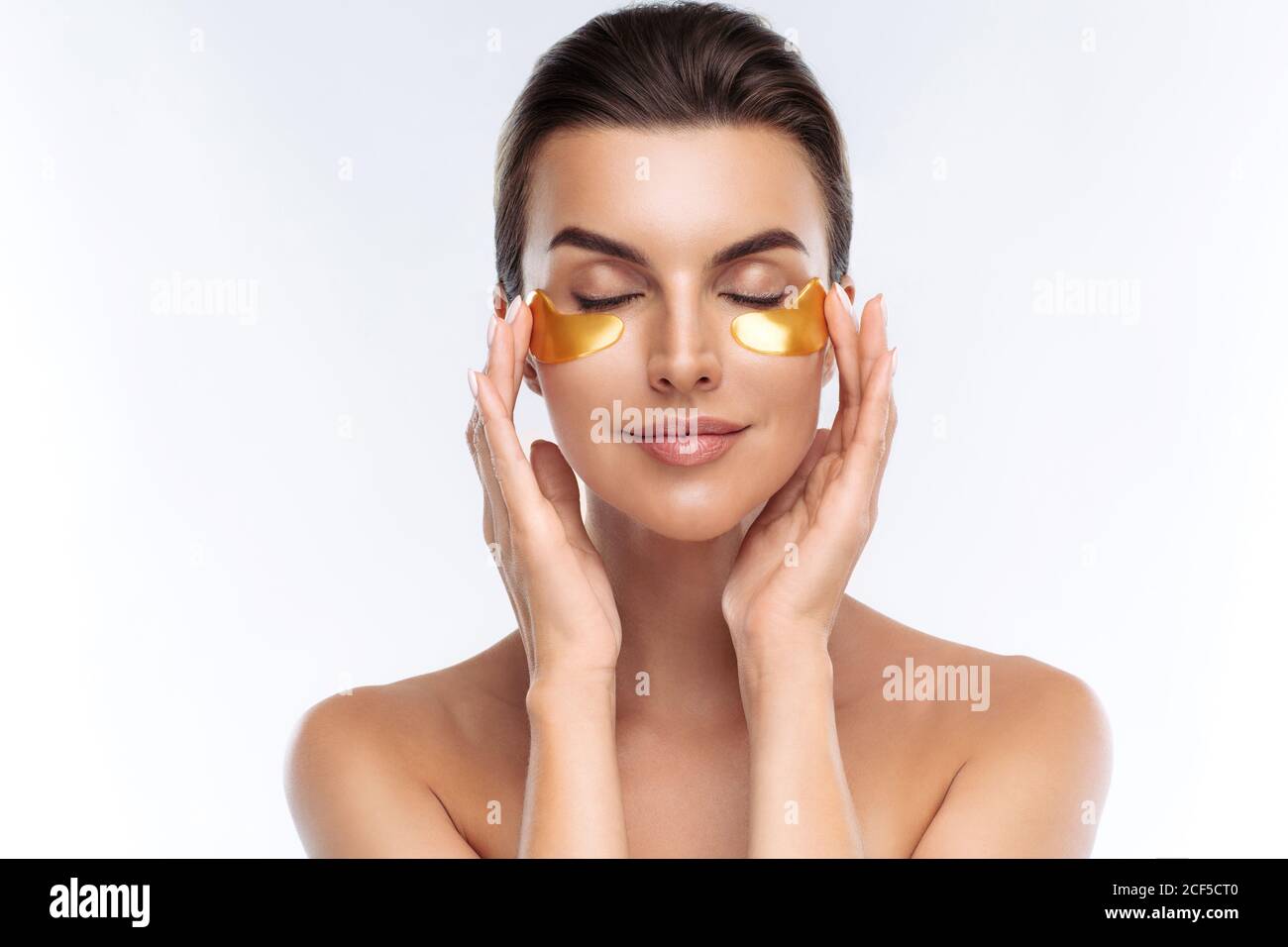 Nahaufnahme Porträt der Schönheit Frau mit natürlichen Make-up Anwendung goldenen Hyaluronic Hydrogel Patches unter den Augen. Junge Erwachsene Weibchen mit sauberer frischer Haut Stockfoto