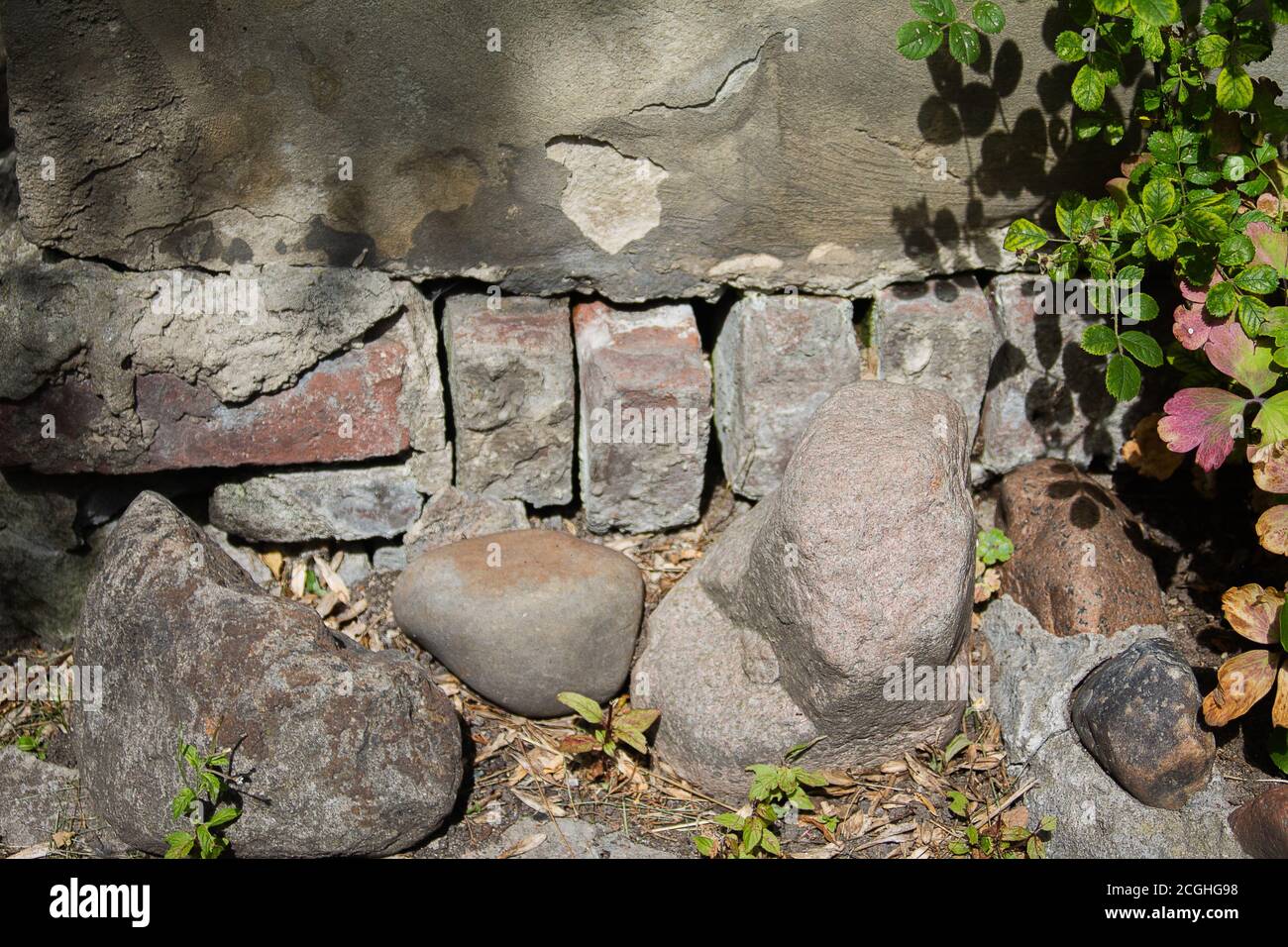 Ausgewaschene Basment. Sie können die Ziegel der Hauswand sehen. Es gibt einige Felsbrocken davor. Stockfoto