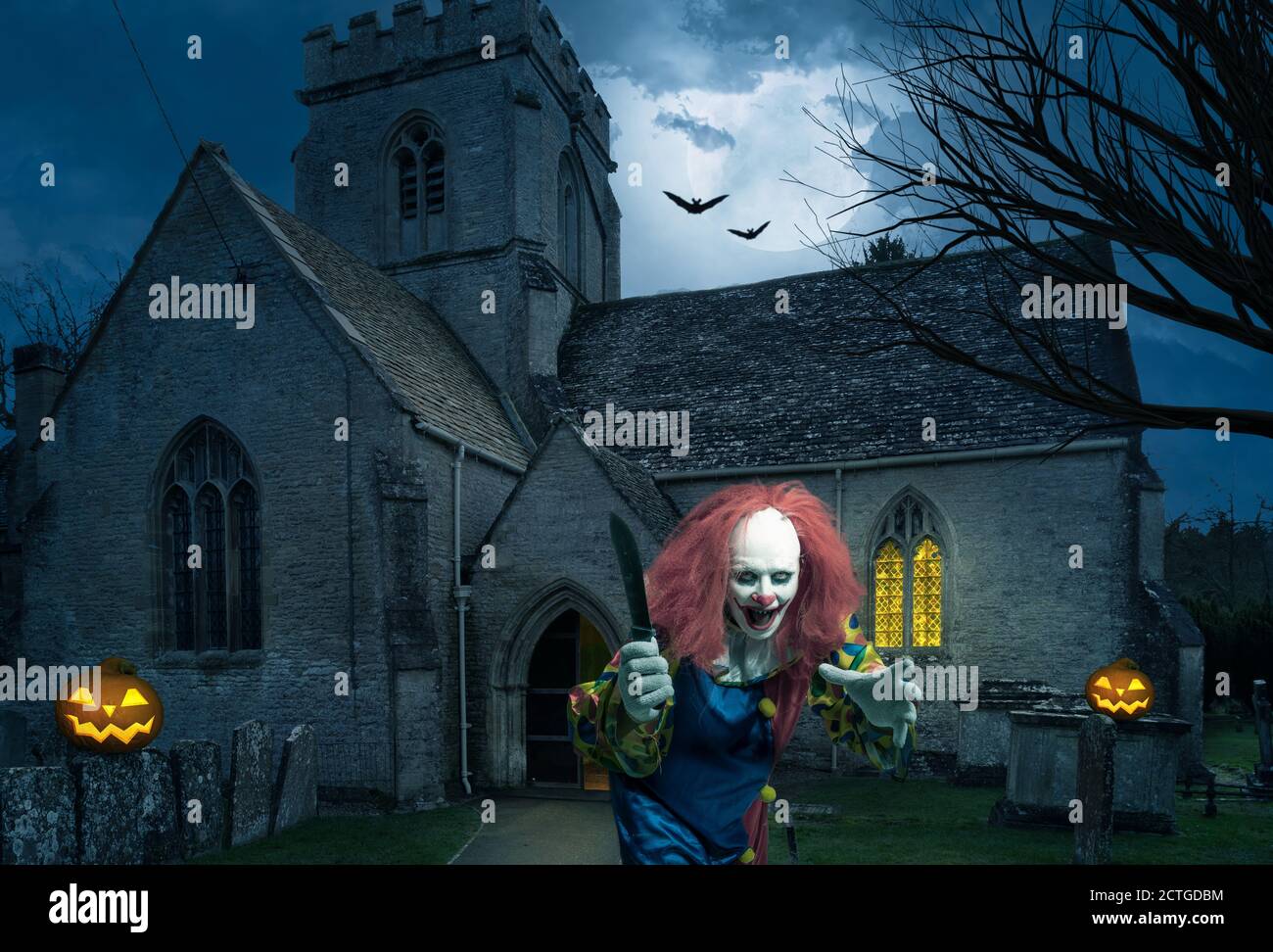 Ein böser Clown mit einem Messer vor einem Alte Kirche Stockfoto