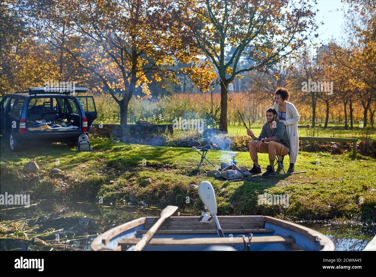 Glückliches junges Paar Angeln am sonnigen Herbst Flussufer Stockfoto