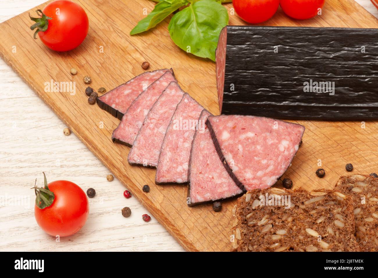 Geräucherte Wurst auf einem Holzbrett mit Kirschtomaten Stockfoto