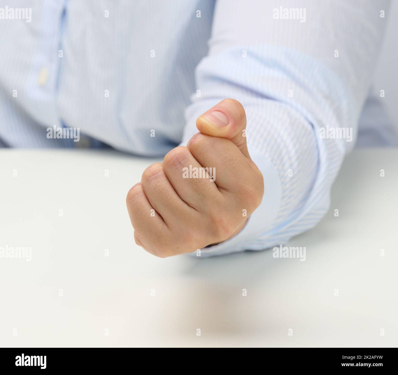 Weibliche Hand zu einer Faust auf einem weißen Tisch gefaltet. Strikte Führung, Aggression und Druck auf die Person Stockfoto