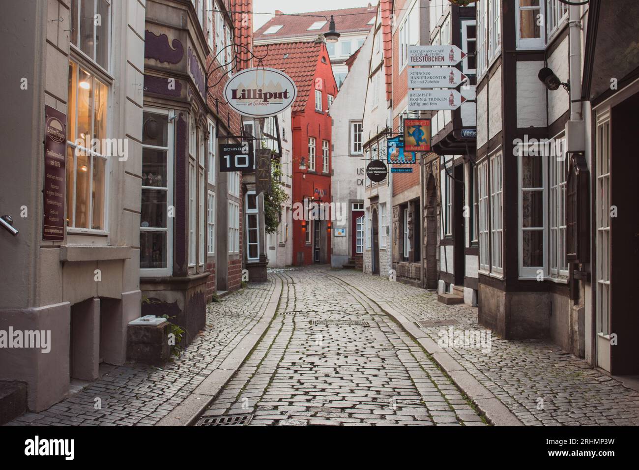 Enge Straße im historischen Stadtteil Schnoor von Bremen. Leere Altstadt mit Geschäften und Häusern in Bremen. Mittelalterliche Gebäude mit Blumen an der Wand. Stockfoto