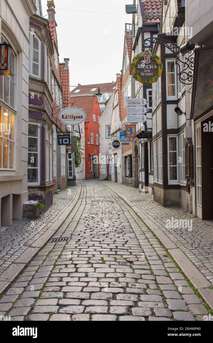 Enge Straße im historischen Stadtteil Schnoor von Bremen. Leere Altstadt mit Geschäften und Häusern in Bremen. Mittelalterliche Gebäude mit Blumen an der Wand. Stockfoto