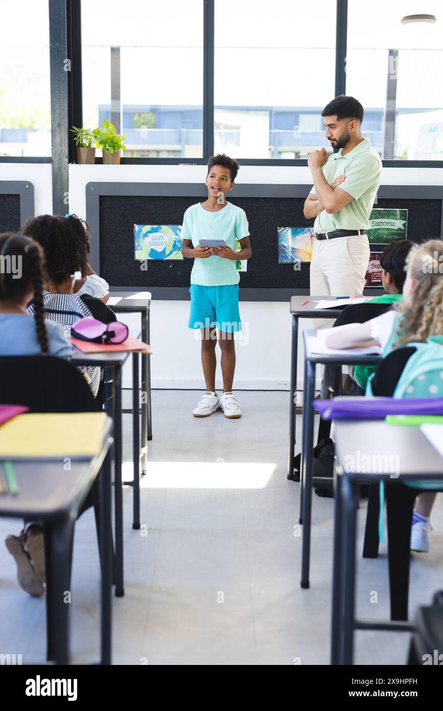 In der Schule präsentiert sich ein junges birassisches Mädchen mit asiatischen männlichen Lehrern Stockfoto