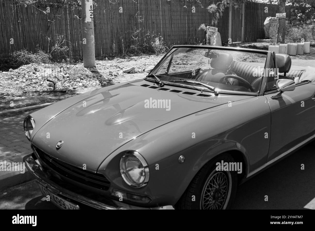 Mitzpe Ramon, Israel, 10. Mai 2024: Fiat 124 Sport Spider Cabriolet mit antikem Sammlerauto parkt auf einer Seitenstraße in Schwarz-weiß Stockfoto