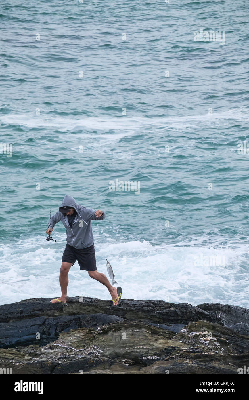 Eine Urlauberin Angeln vom Felsen am Fistral in Newquay, Cornwall. Stockfoto