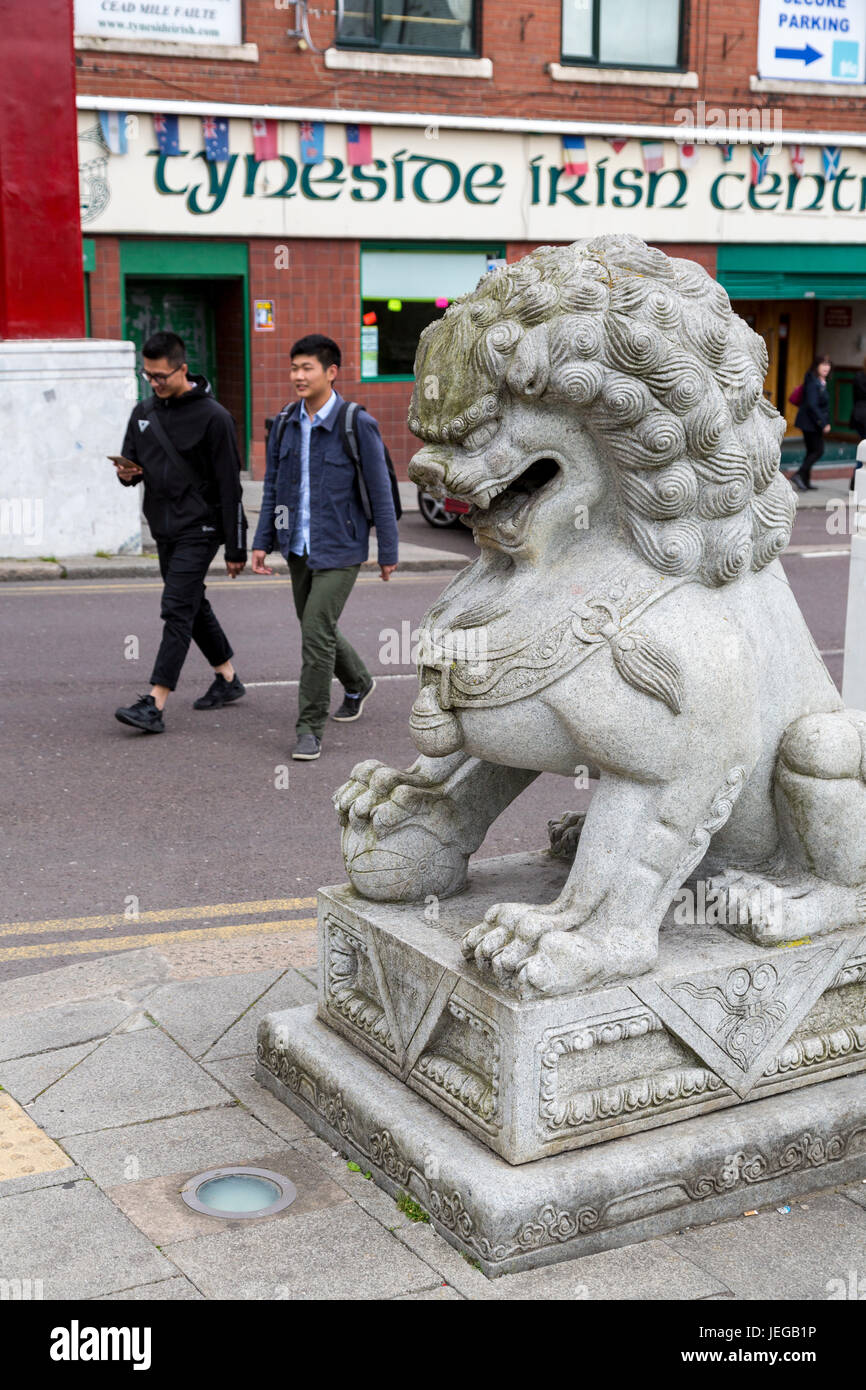 Newcastle-upon-Tyne, England, Vereinigtes Königreich.   Guardian Lion (Shi oder Foo Hund) am Eingang zu Chinatown.  Kulturelle Vielfalt: Irish Centre im Hintergrund. Stockfoto