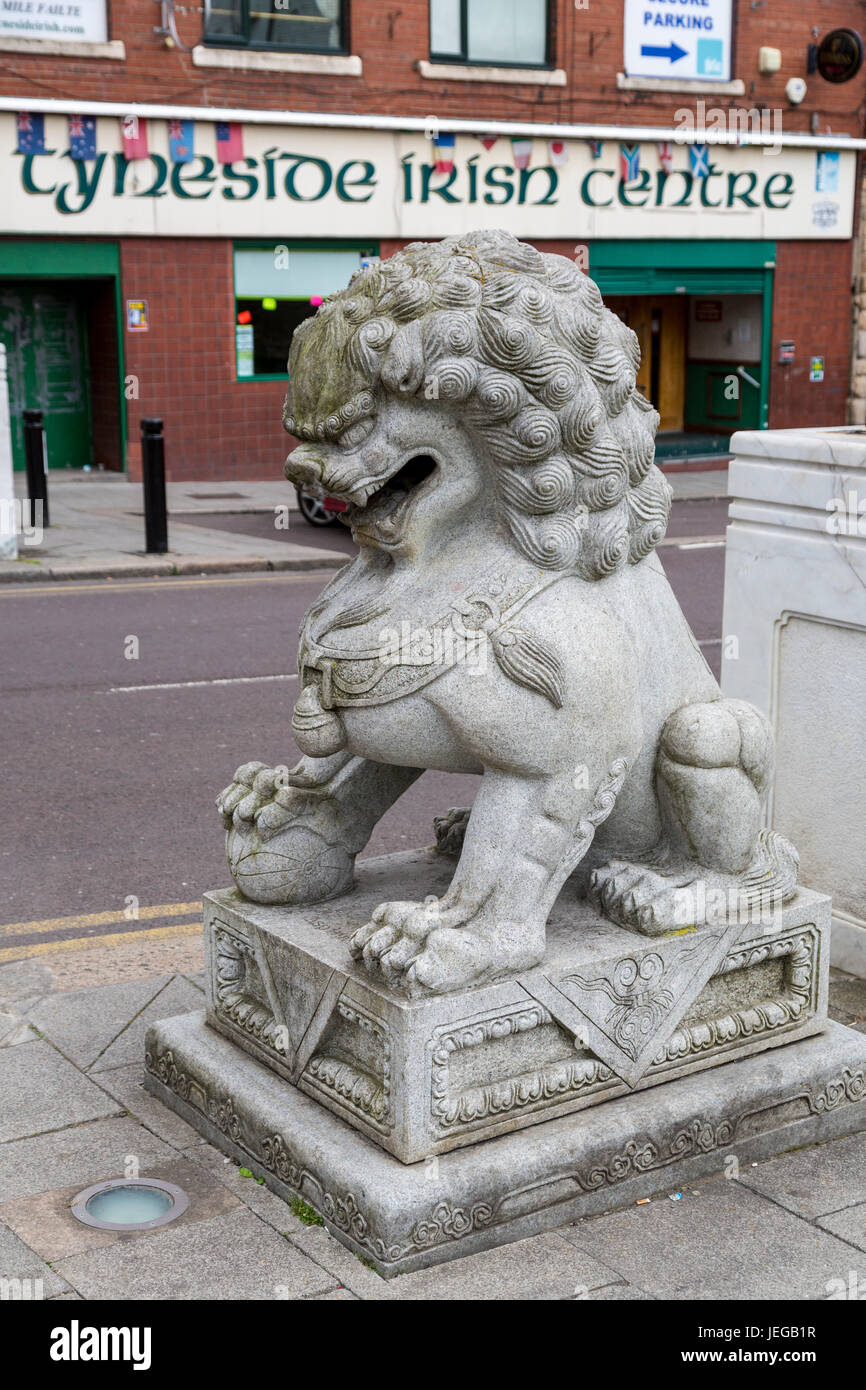 Newcastle-upon-Tyne, England, Vereinigtes Königreich.   Guardian Lion (Shi oder Foo Hund) am Eingang zu Chinatown.  Kulturelle Vielfalt: Irish Centre im Hintergrund. Stockfoto