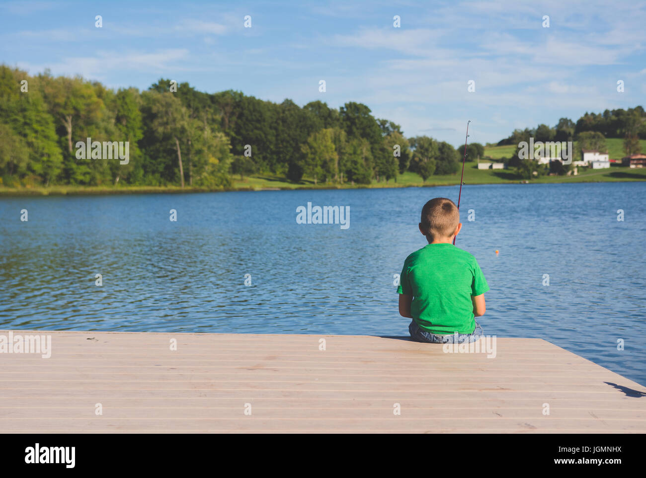 Ein Kind, Angeln an einem Dock an einem Teich in einer ländlichen Gegend. Stockfoto