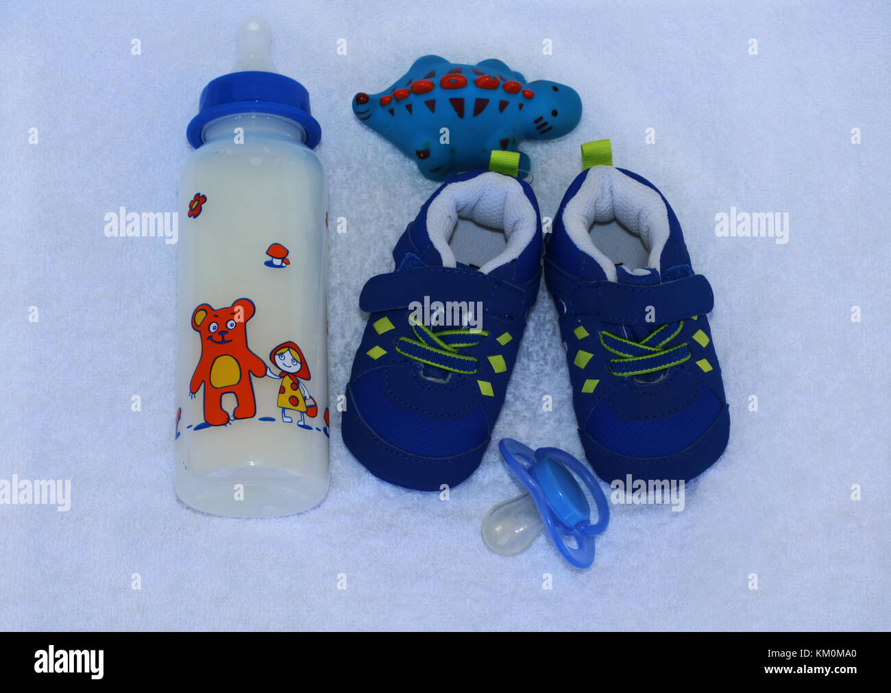 Baby Sachen für Jungen. Der trendige Mode Kleidung und Kinder Material für kleine Baby Boy. Baby Milch, Spielzeug, Schnuller, blau altmodische winzige Turnschuhe auf Weiß Stockfoto