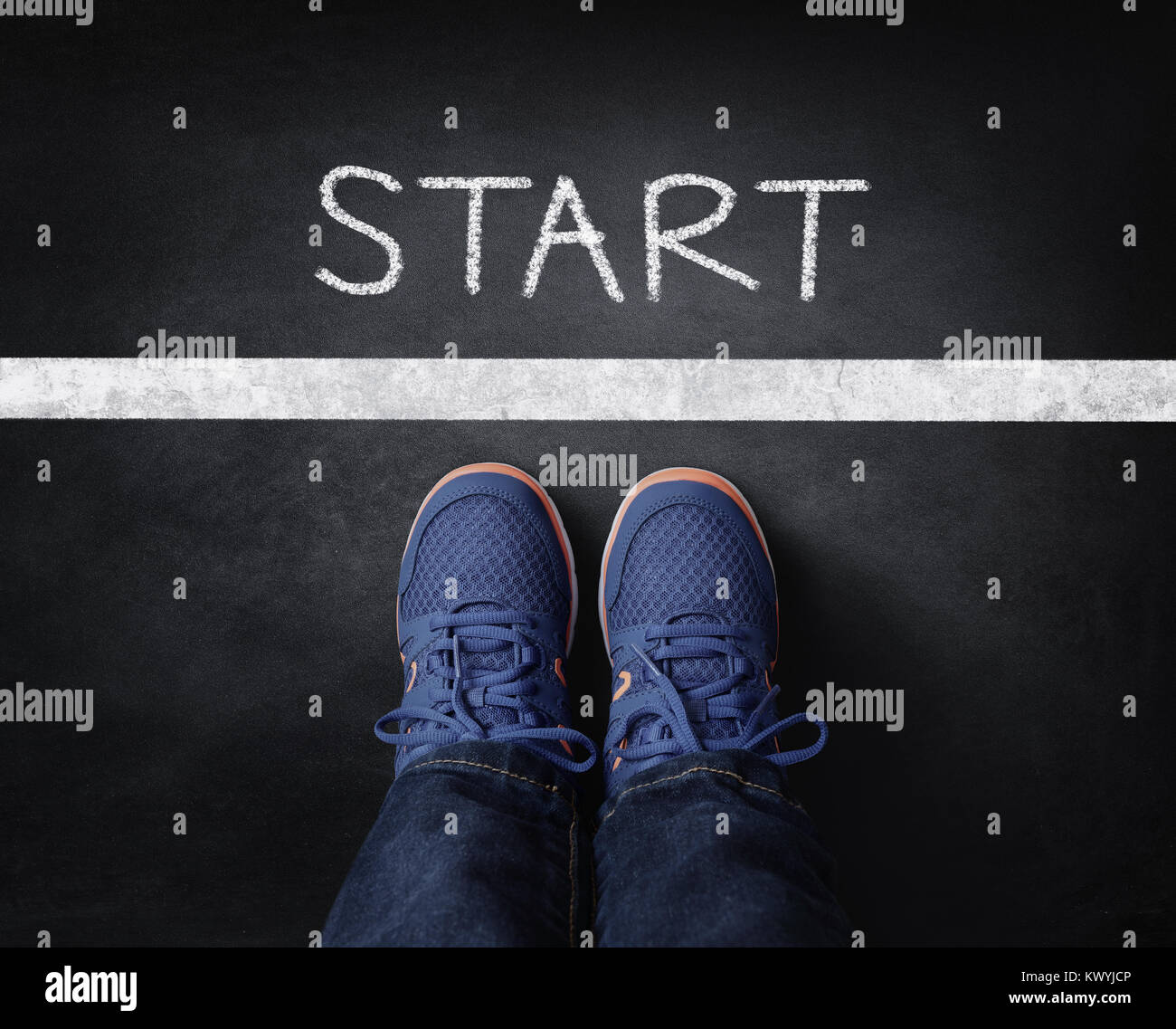 Start Kind in Turnschuhen steht neben Chalk Start auf der Tafel Stockfoto