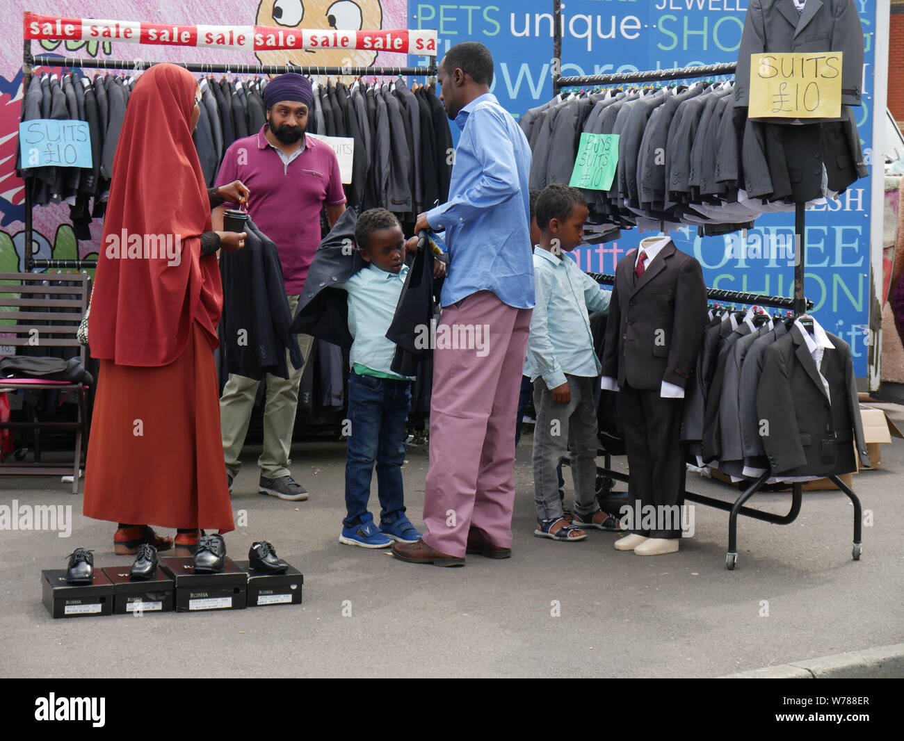 Familie Einkauf für die Jungen Anzüge auf einem Markt im Freien in England Großbritannien, ein Junge versucht, auf eine Jacke, während die Eltern einen Preis verhandeln. foto DON TONGE Stockfoto