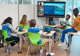 School kids using Dell laptops and Dell interactive touchscreen and webcam technology during a class session.