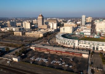 Ariel view over Fresno, California, with fire station and baseball stadium and commercial buildings against the daytime skyline.