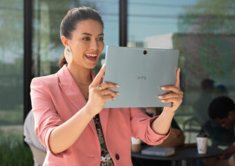 Young business woman holds a Dell XPS 9315 2-in-1 up in tablet mode for a video conference.