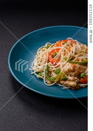 Tasty dish of Asian cuisine with rice noodles, chicken, asparagus, pepper, sesame seeds 108352119